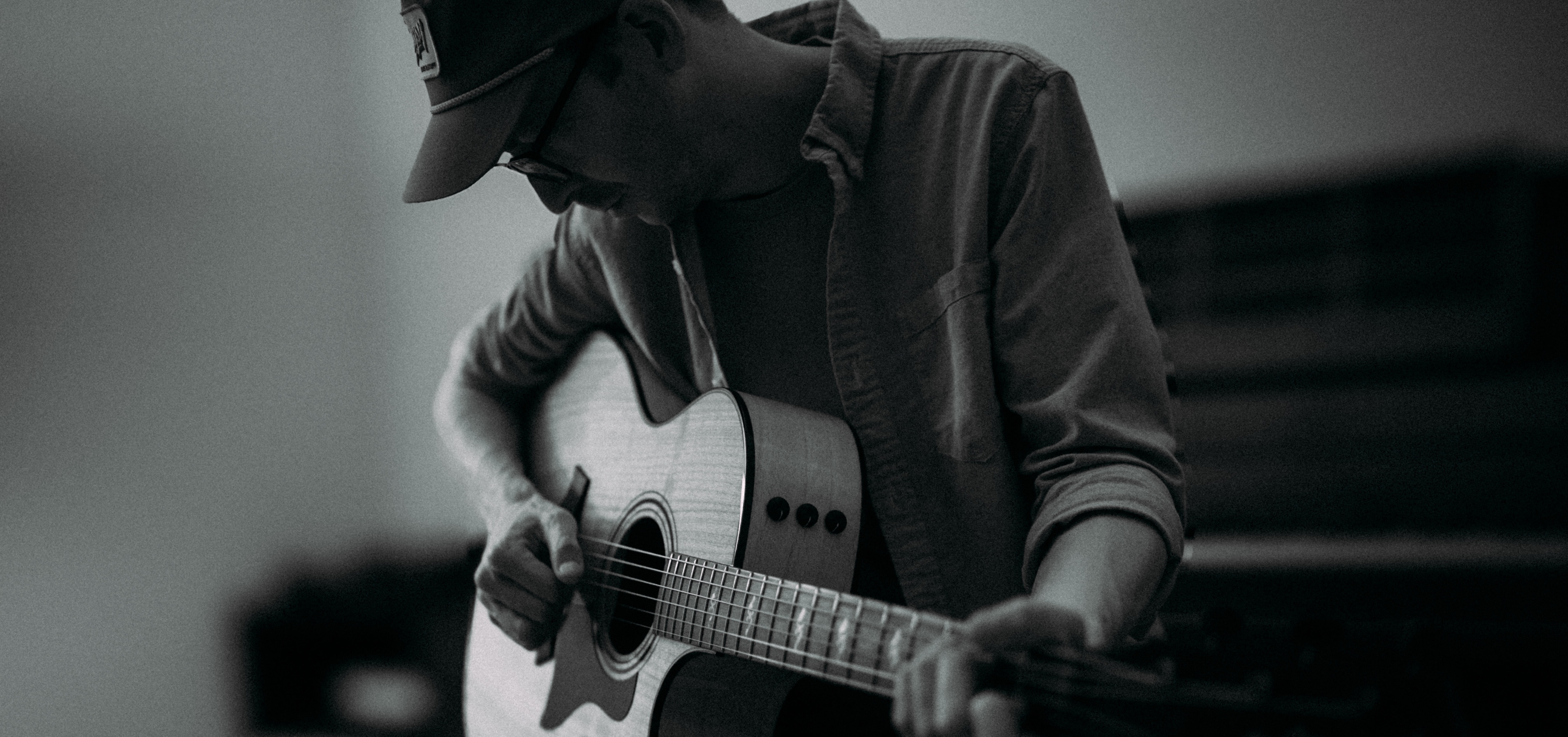 Brent Pendergraft sitting on a piano bench playing the guitar