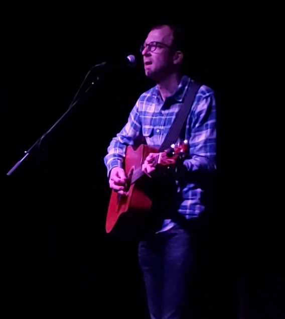 Brent Pendergraft playing the guitar and singing into a microphone